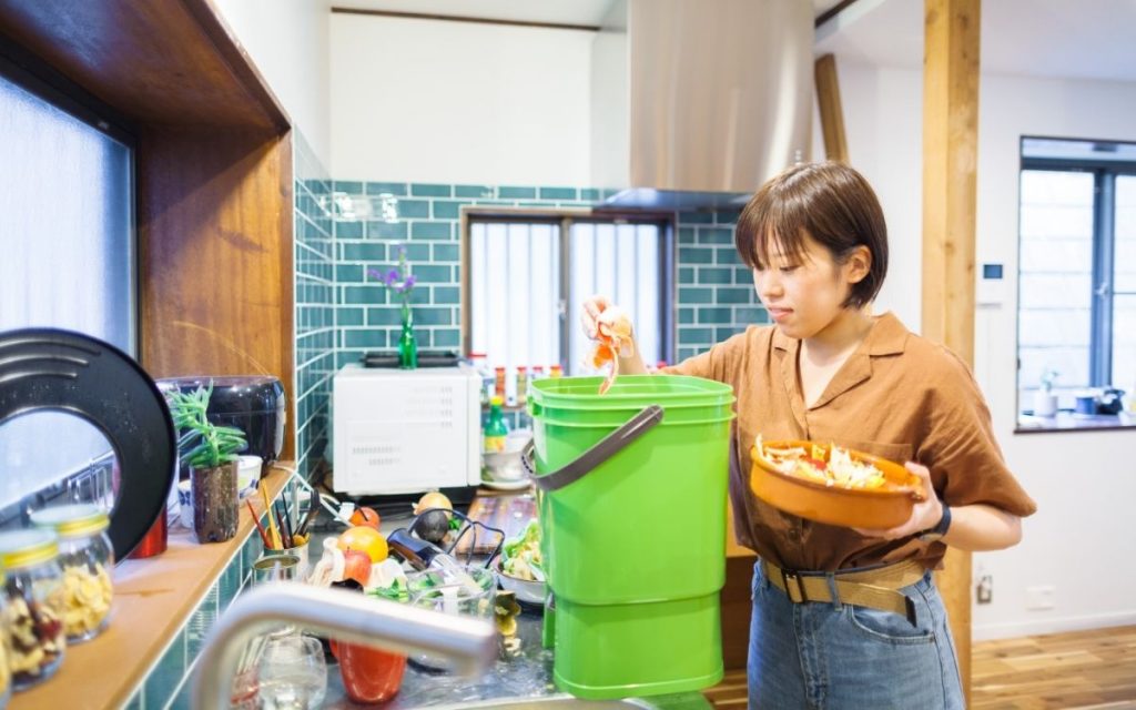 A women is putting food scraps in a bokashi compost bin