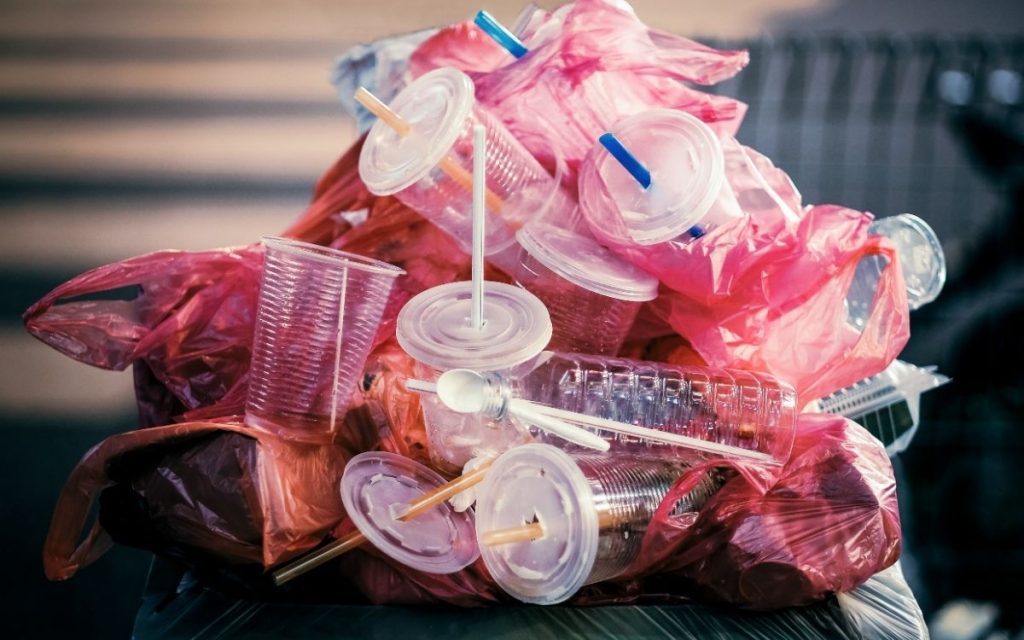 Assorted plastics overflowing from a trash bin.
