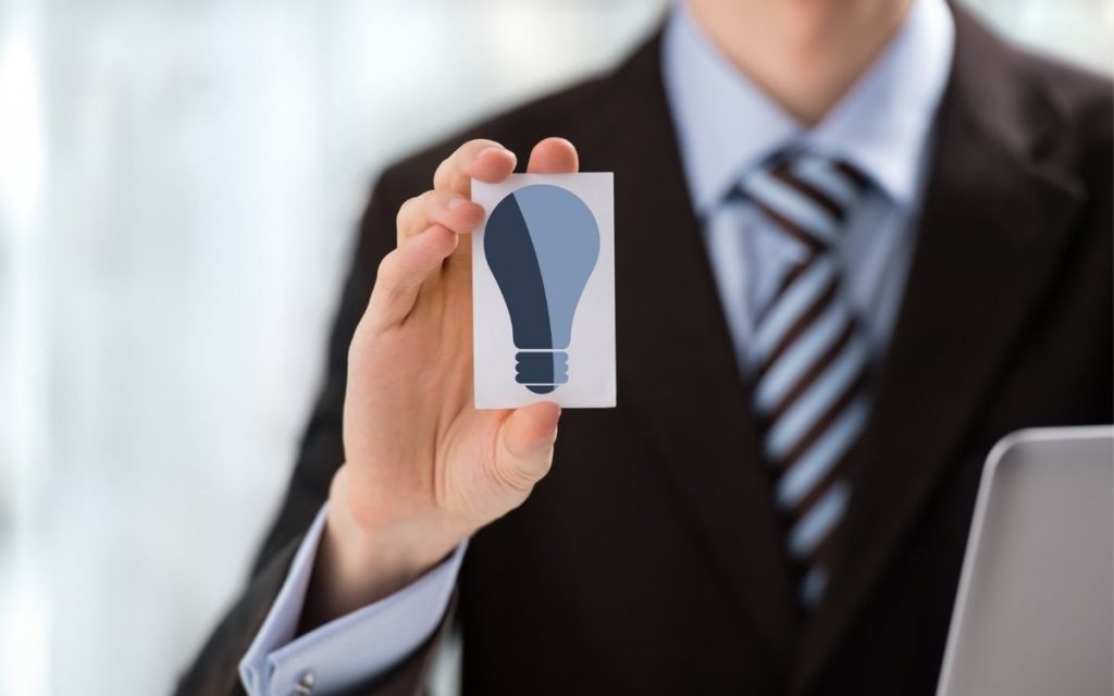 business man holds picture of a light bulb 