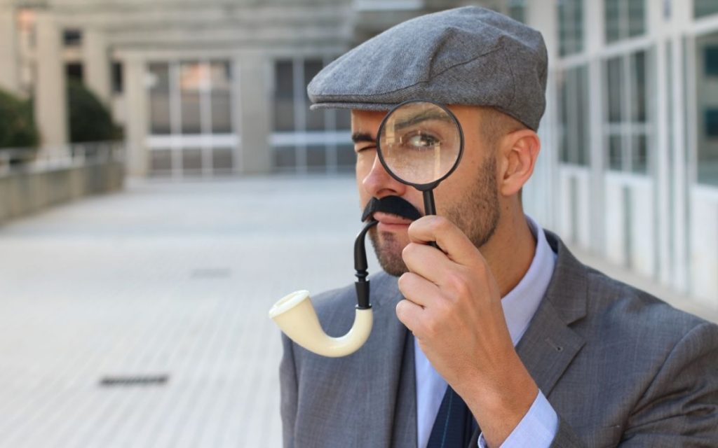 man looking through a magnifying glass with a pipe.