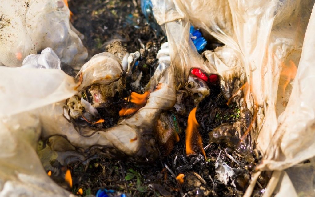 plastic waste burns in a trash bin 