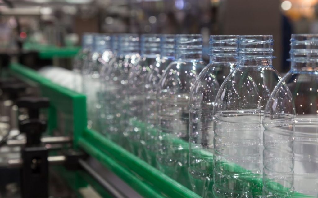 empty plastic bottles sit empty on a conveyor belt in a factory awaiting to be filled