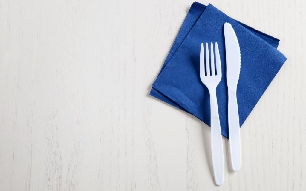 Plastic fork and knife with napkin sit on a table.