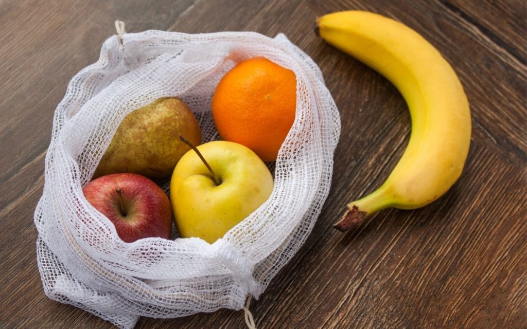 fruits sit in a reusable produce bag on top of a table