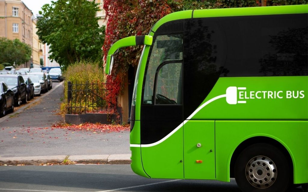 green electric bus next to curb