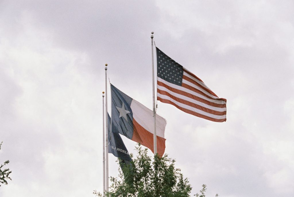 texas flag american flag waving against grey sky